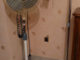 un ventilateur posé sur un pied dans une pièce