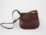 un vieux sac à main en cuir marron muni d'une bandoulière, sur fond blanc