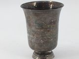 a silver cup that is sitting on a white surface