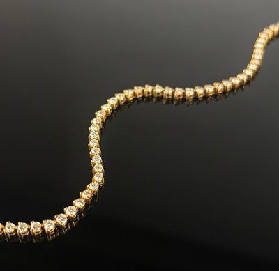a yellow gold necklace with diamonds on a black surface