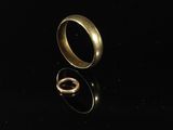 two gold wedding rings sitting on top of a black surface