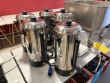 plusieurs cafetières en acier inoxydable posées sur le plan de travail d'une cuisine