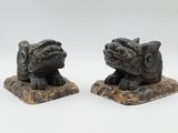 these are two statues of a dog and a cat sitting on a rock