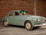 a green car that is parked in front of a brick wall
