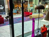 Des vases aux couleurs vives sont disposés devant une vitrine dans un centre commercial
