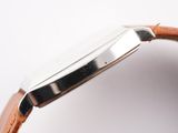 the back of a watch with a brown leather strap on a white surface