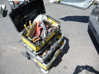 une boîte à outils jaune posée par terre et remplie d'outils divers