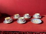 six tasses et soucoupes posées sur une table rouge