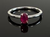 silver ring with a ruby stone on a black surface