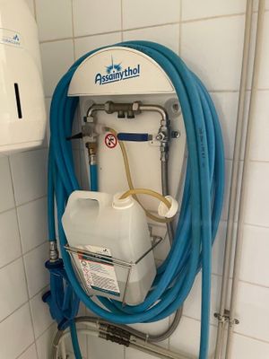 un tuyau bleu raccordé à un réservoir blanc dans une salle de bains