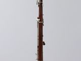 an old bassoon on a clear stand against a white background