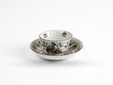 a close up of a cup and saucer on a white surface