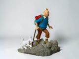 figurine of a man with a backpack and a dog on a rock