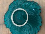 a teal colored bowl with a white rim on a wooden table