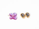 two pairs of earrings on a white surface with a flower in the middle