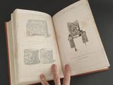 a hand that is holding a book open on a table