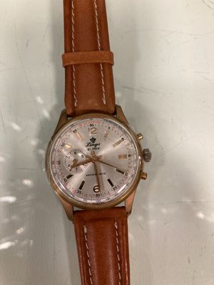 an image of a watch with a brown leather strap on a white surface