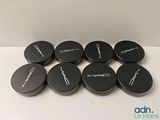six couvercles de macarons noirs avec une inscription blanche, posés sur une surface blanche