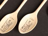 three wooden spoons with drawings on them sitting next to a penny