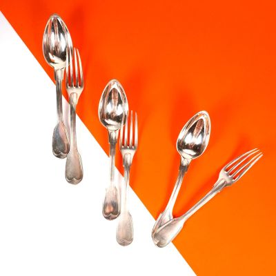 trois fourchettes et deux cuillères sur un fond orange et blanc
