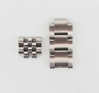 un gros plan d'une montre posée sur une surface blanche, avec un bracelet en métal