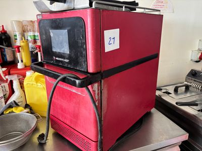 un micro-ondes rouge posé sur un plan de travail en métal