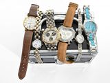 de nombreuses montres et bracelets dans un coffret posé sur une surface blanche