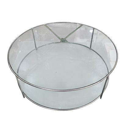 une table ronde en verre avec un piètement en métal et un plateau en verre