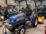 a blue tractor parked in a garage with other vehicles