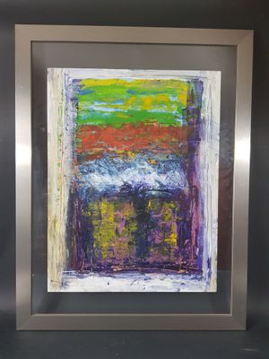 un tableau abstrait dans un cadre argenté accroché à un mur noir