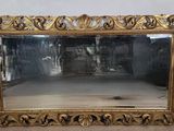 un miroir au cadre doré ouvragé posé sur un parquet