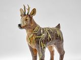 une figurine représentant un cerf debout sur une surface blanche