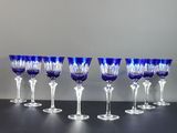 six verres à vin bleus sont alignés sur une table noire