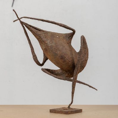 sculpture représentant un oiseau, posée sur un socle en bois, elle-même posée sur une table