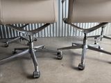 pair of leather office chairs on casteors in front of a corrugated wall
