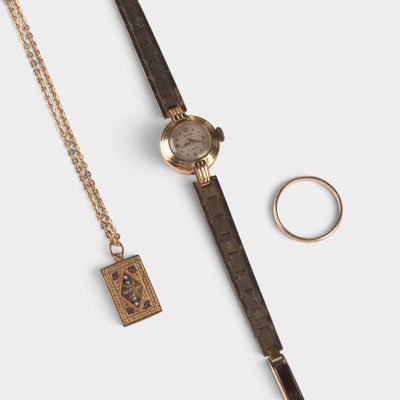 un gros plan d'une montre et d'une bague posées sur une surface blanche