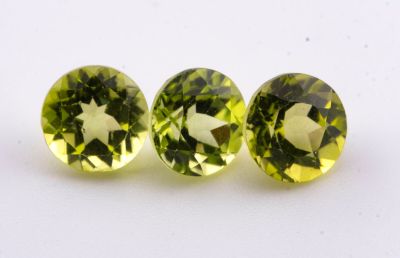 une paire de trois tourmalines vertes posées sur une surface blanche