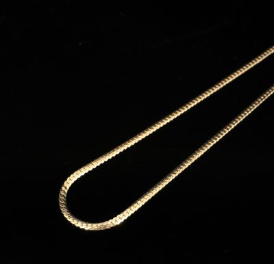 un gros plan d'un collier en or avec une chaîne sur fond noir