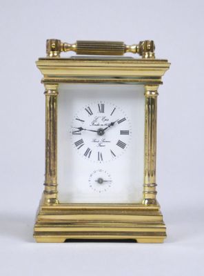 une petite horloge en or avec des chiffres romains