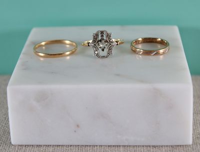 trois bagues en or et en argent posées sur un bloc de marbre