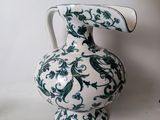 a white and green vase with a bird on it