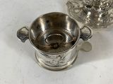 two silverplated cups and saucers on a white table