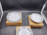 trois assiettes blanches parsemées de points noirs, posées sur une boîte