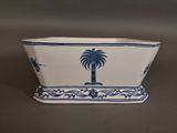 a blue and white planter with a palm tree on it