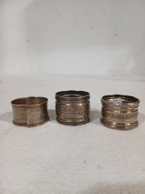 trois bagues en argent de styles différents posées sur une surface blanche