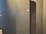 a picture of a bathroom with a toilet and a black wall
