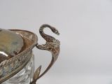 a silver vase with a bird on top of it