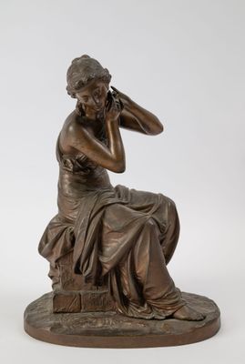 a bronze statue of a woman sitting on a rock with her hand on her head