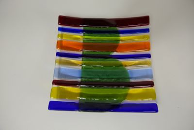 une assiette en verre multicolore posée sur une table blanche