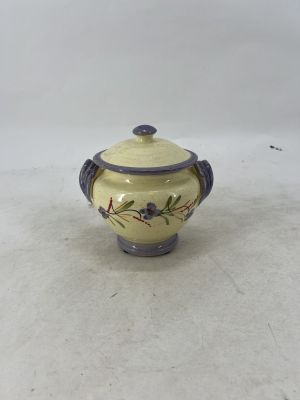 a small yellow and purple vase with a lid